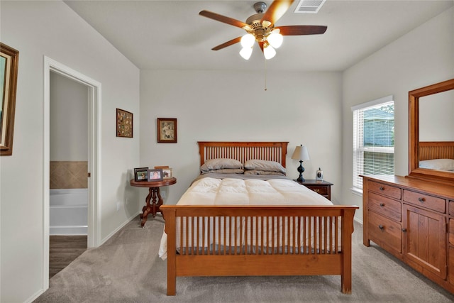 bedroom with visible vents, ensuite bathroom, a ceiling fan, light carpet, and baseboards