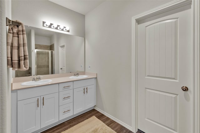 full bath featuring double vanity, a stall shower, a sink, and wood finished floors