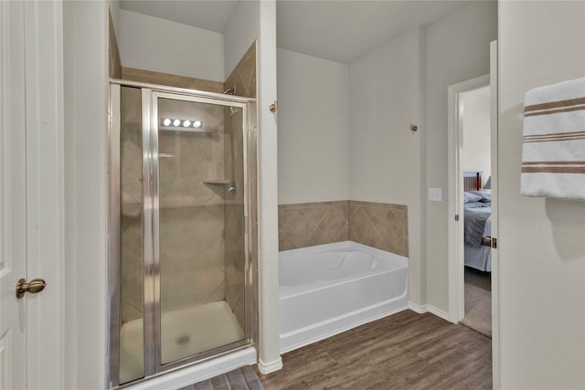 bathroom featuring a stall shower, a garden tub, ensuite bath, and wood finished floors