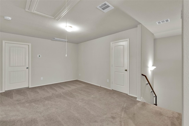 empty room with attic access, visible vents, and carpet flooring