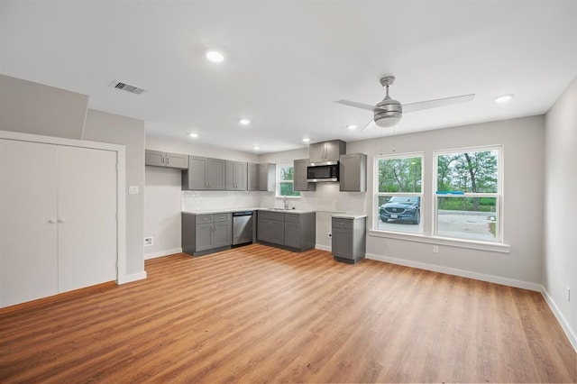 kitchen with light wood finished floors, stainless steel appliances, visible vents, gray cabinetry, and baseboards