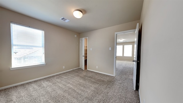 spare room featuring carpet, visible vents, and baseboards