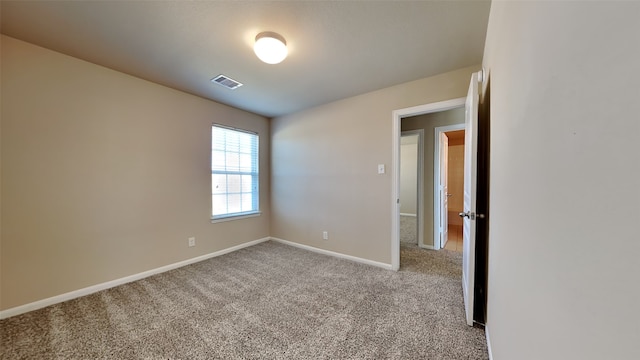 carpeted spare room featuring visible vents and baseboards