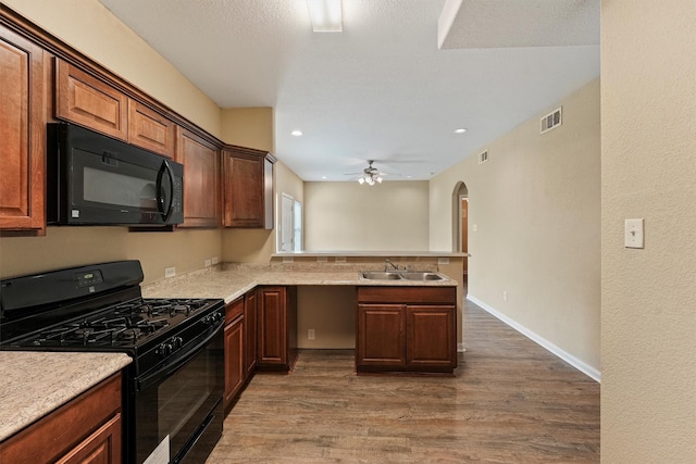 kitchen with visible vents, wood finished floors, a peninsula, light countertops, and black appliances