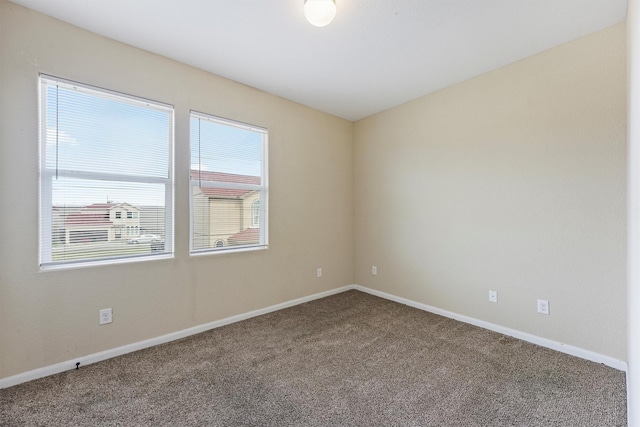 carpeted empty room featuring baseboards