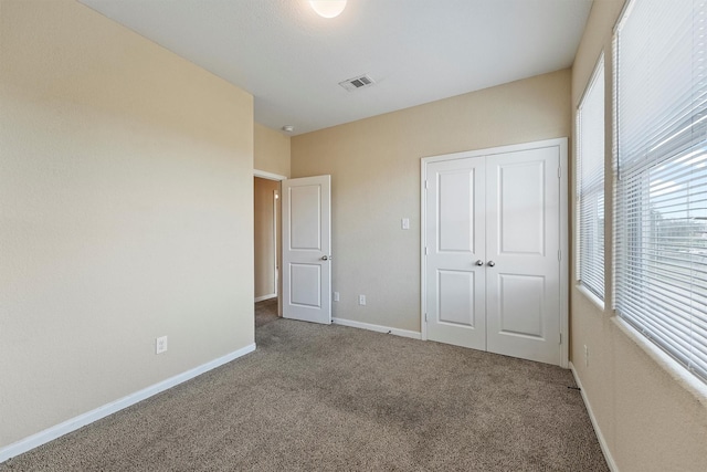 unfurnished bedroom with carpet floors, a closet, visible vents, and baseboards