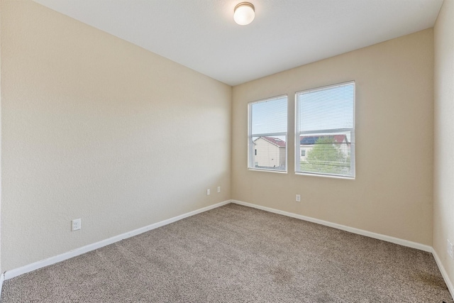 empty room featuring carpet and baseboards