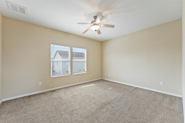 carpeted empty room featuring baseboards, a textured ceiling, visible vents, and a ceiling fan