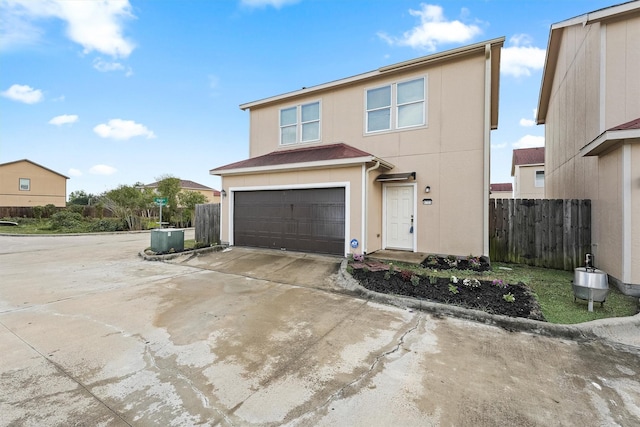 traditional-style home featuring concrete driveway, an attached garage, fence, and stucco siding