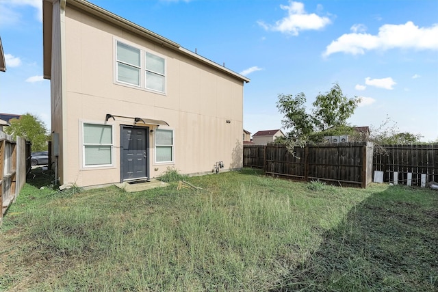 back of house with a fenced backyard and a lawn