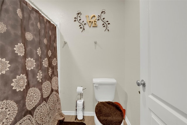 bathroom featuring a shower with shower curtain, wood finished floors, toilet, and baseboards