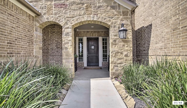 doorway to property featuring stone siding and brick siding