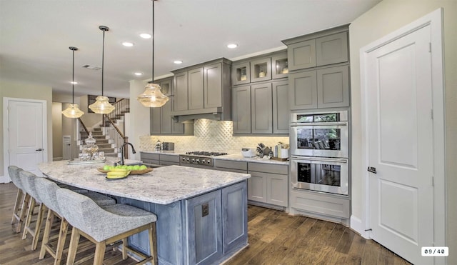 kitchen featuring appliances with stainless steel finishes, decorative backsplash, a sink, and gray cabinetry