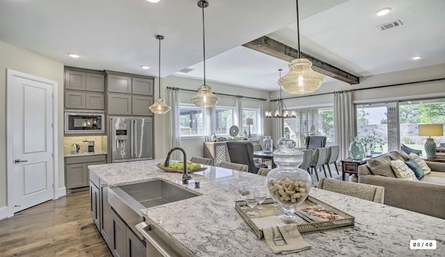 kitchen with stainless steel appliances, visible vents, gray cabinetry, open floor plan, and a sink