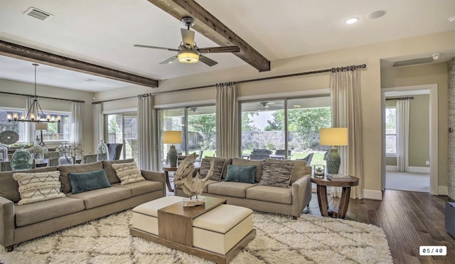 living area with ceiling fan with notable chandelier, dark wood-type flooring, visible vents, baseboards, and beam ceiling