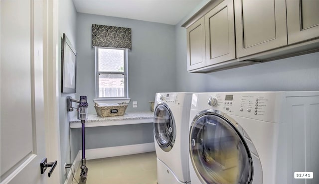 clothes washing area with cabinet space, washing machine and dryer, light tile patterned floors, and baseboards