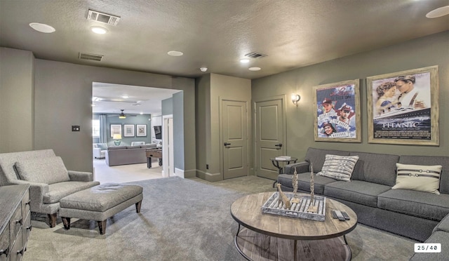 living area with visible vents, a textured ceiling, and light colored carpet