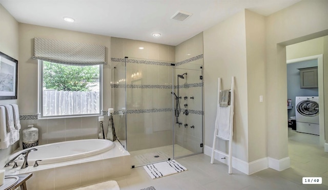 bathroom with washer / dryer, a stall shower, a garden tub, and baseboards