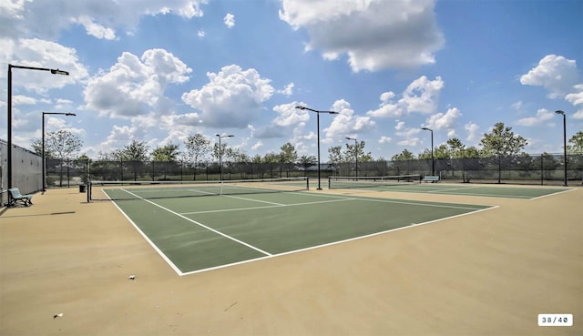 view of tennis court featuring community basketball court and fence