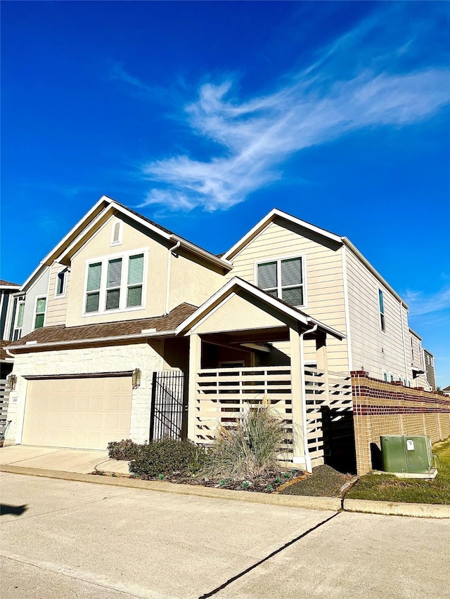 townhome / multi-family property featuring fence, a garage, driveway, and stucco siding