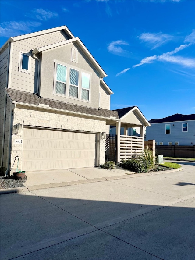 traditional-style home with fence, roof with shingles, stucco siding, a garage, and driveway