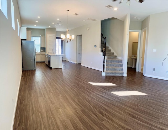 unfurnished living room featuring recessed lighting, stairway, baseboards, and dark wood-style flooring