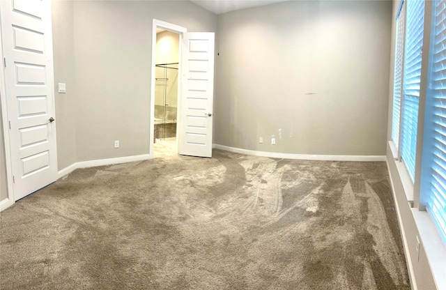 unfurnished bedroom featuring connected bathroom, baseboards, and carpet flooring