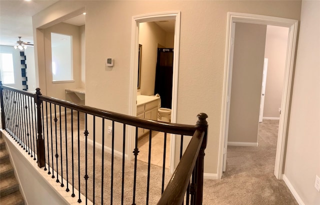 hallway featuring an upstairs landing, carpet, and baseboards