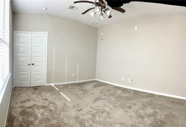 unfurnished bedroom featuring baseboards, visible vents, lofted ceiling, a closet, and carpet flooring