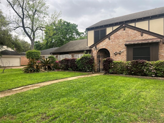 english style home featuring a garage, brick siding, stucco siding, and a front yard