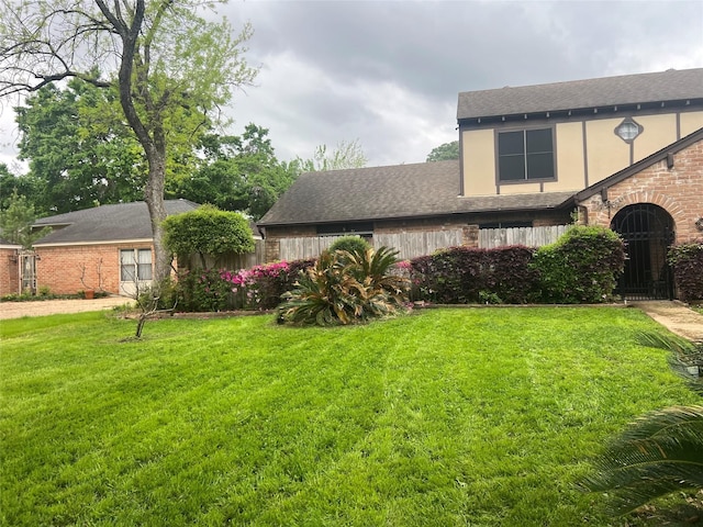 view of front of house with a shingled roof, a front yard, fence, and stucco siding