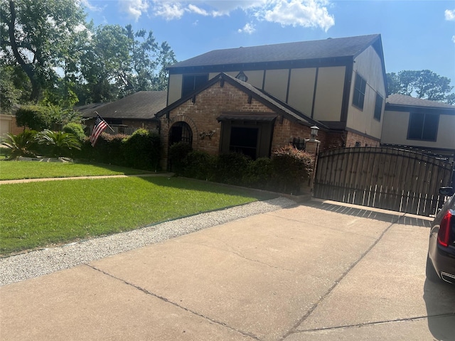 8111 Ivan Reid Dr, Houston, TX 77040 - tudor house featuring brick siding, driveway, a front lawn, a gate, and roof with shingles