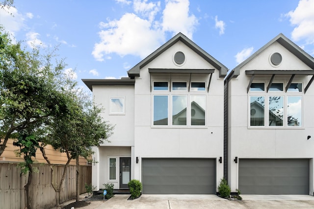 view of front of house with stucco siding, concrete driveway, and fence