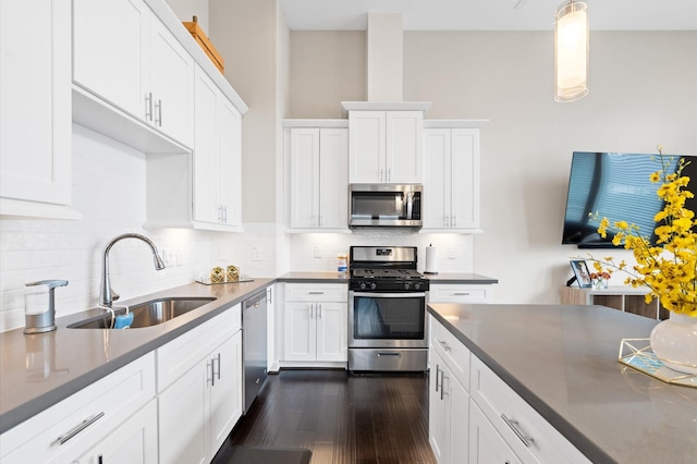 kitchen featuring dark wood-style floors, a sink, stainless steel appliances, white cabinets, and tasteful backsplash