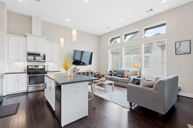 kitchen with a breakfast bar area, visible vents, appliances with stainless steel finishes, and dark wood-style floors