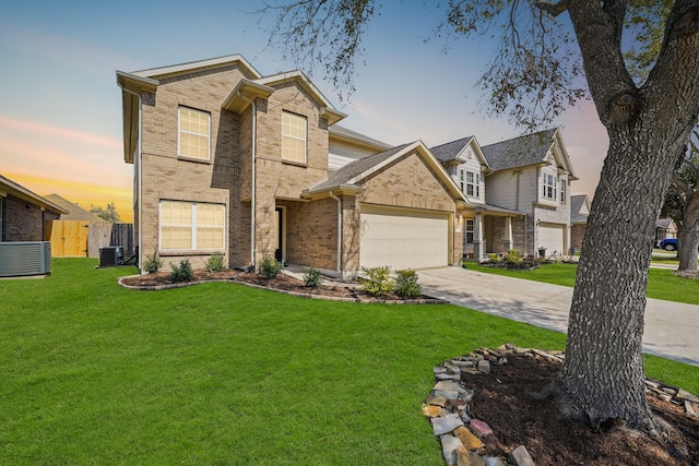 traditional-style home featuring brick siding, concrete driveway, a lawn, an attached garage, and fence