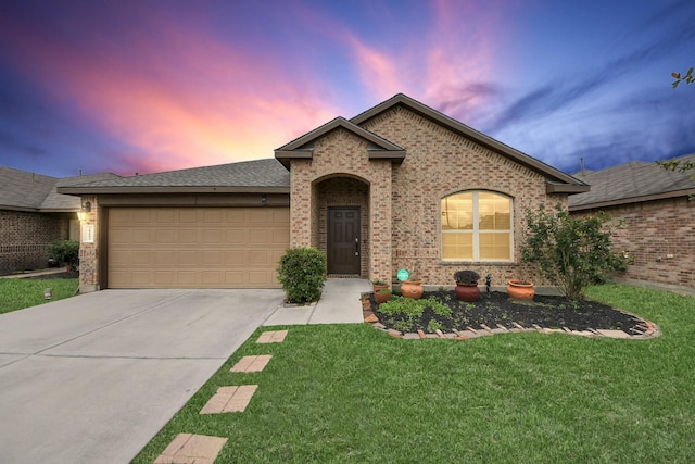 ranch-style home with an attached garage, brick siding, concrete driveway, a yard, and roof with shingles