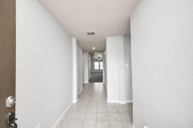 corridor with light tile patterned flooring, visible vents, and baseboards