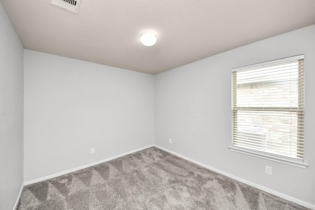 spare room featuring carpet, visible vents, and baseboards