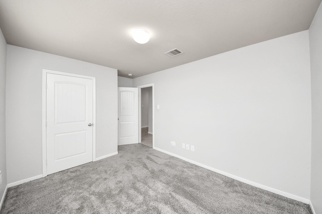 carpeted empty room featuring visible vents and baseboards