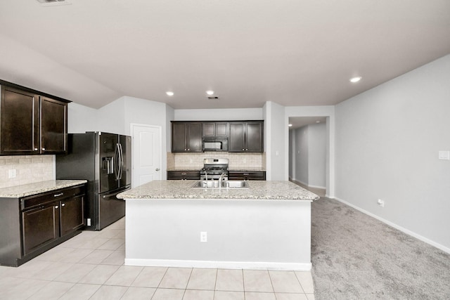 kitchen with dark brown cabinets, appliances with stainless steel finishes, a sink, and a center island with sink