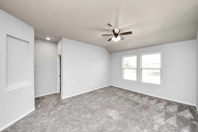 empty room with carpet flooring, visible vents, baseboards, vaulted ceiling, and a ceiling fan