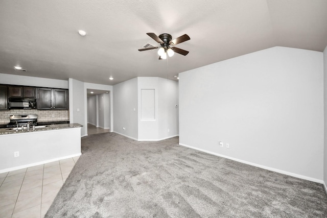 unfurnished living room featuring light carpet, light tile patterned floors, baseboards, lofted ceiling, and ceiling fan