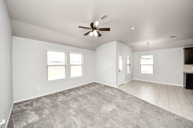 unfurnished living room featuring light tile patterned flooring, light colored carpet, ceiling fan with notable chandelier, visible vents, and vaulted ceiling