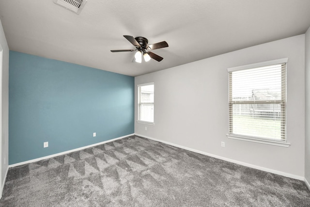 carpeted spare room featuring visible vents, ceiling fan, and baseboards