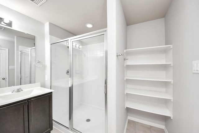 full bath featuring a stall shower, vanity, baseboards, and tile patterned floors