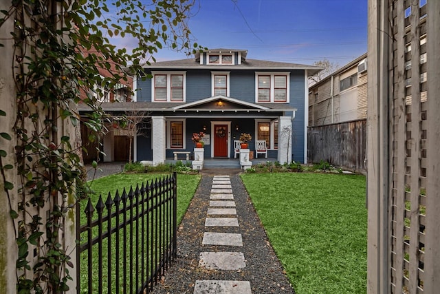 american foursquare style home featuring fence, a porch, and a front yard