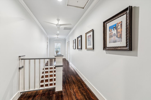 hallway with visible vents, baseboards, dark wood-style flooring, crown molding, and an upstairs landing