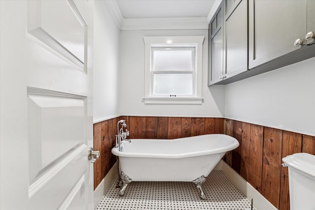 bathroom featuring crown molding, a freestanding bath, toilet, wainscoting, and wood walls