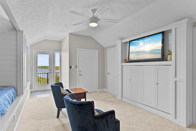 living area featuring vaulted ceiling, ceiling fan, a textured ceiling, and light colored carpet